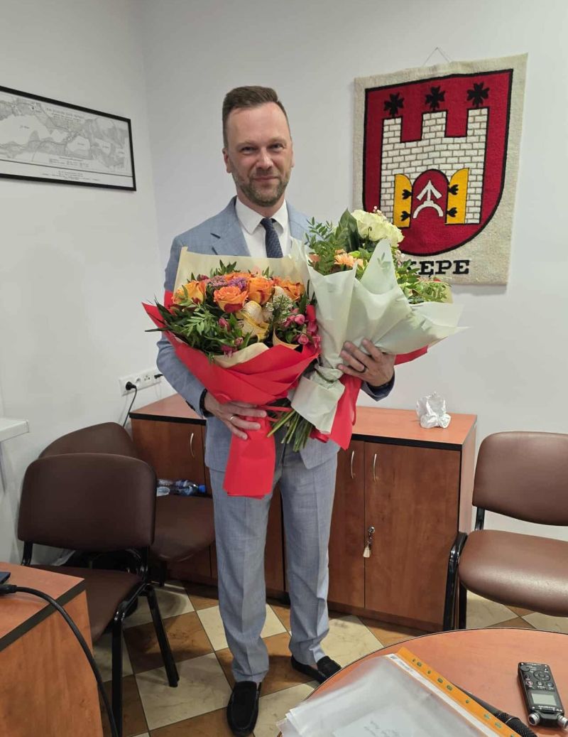 Burmistrz z otrzymanymi kwiatami podczas sesji.